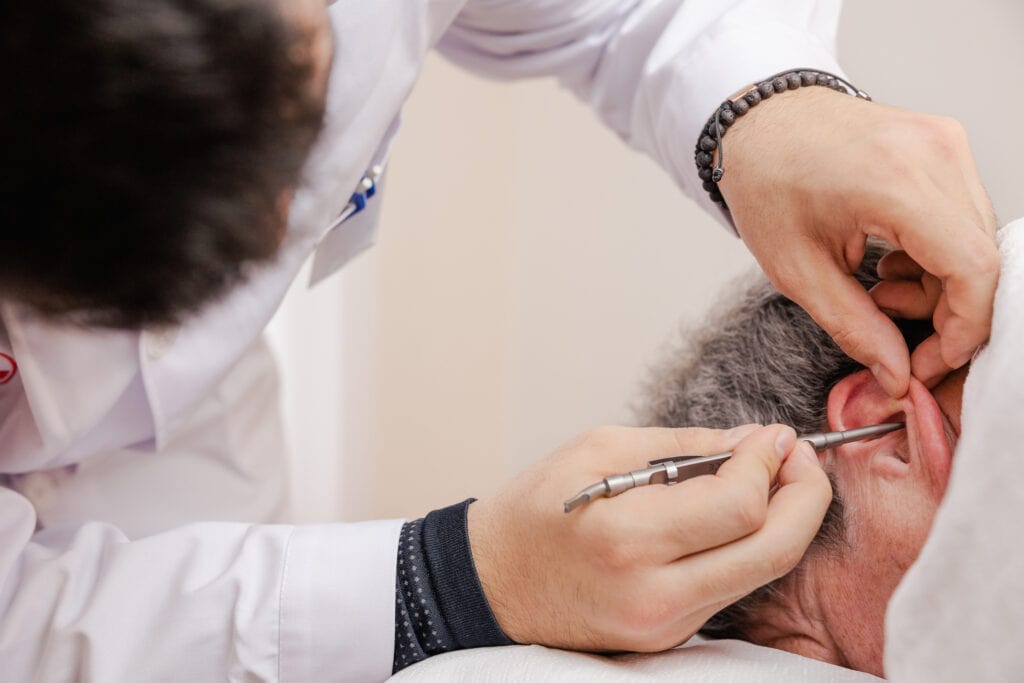 Therapeut führt Ohrakupunktur bei Patient durch